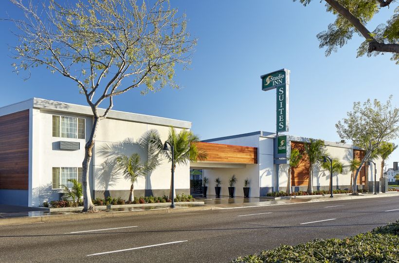 The image shows a modern hotel building with a sign reading 