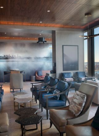 A luxurious lounge with plush seating, large windows offering a scenic view, a mural on the wall, and ambient lighting creating a cozy atmosphere.